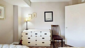 A bedroom with a bed, a dresser, a chair, and a door. - Sea and Sails Retreat (Myrtle Beach)