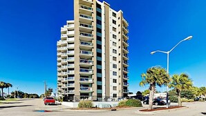 A multi-story residential building with balconies, a street in front, and a clear blue sky. - Sea and Sails Retreat (Myrtle Beach)
