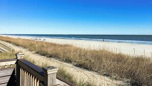 A beach view with a wooden boardwalk leading to the shore, sandy beach, and ocean. - Sea and Sails Retreat (Myrtle Beach)