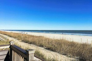 Blick auf den Strand mit einer Holzpromenade, die zum Ufer führt, Sandstrand und Meer.