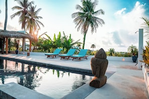A pool area with lounge chairs and a stone sculpture.