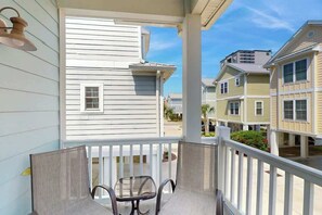 A balcony with a white railing, a chair, and a small table. - Kashton Charms Retreat (Myrtle Beach)