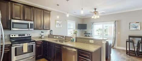 A modern kitchen with dark wood cabinets, stainless steel appliances, and a large island with a sink.