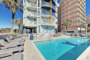A hotel with a swimming pool, multiple balconies, and lounge chairs. - Lighthouse Corner Getaway (Myrtle Beach)