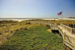 Ein hölzerner Steg führt zu einem Strand mit einer US-amerikanischen Flagge.