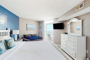 A hotel room with a bed, a television, a dresser, and a balcony with a view. - Bay Watch Resort 1712 (North Myrtle Beach)