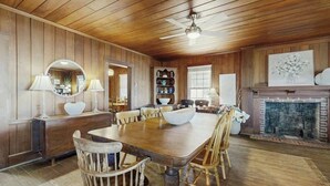 Un coin repas avec une table et des chaises en bois, une cheminée et un ventilateur de plafond.