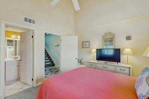 Ein Schlafzimmer mit Bett, Fernseher, Kommode und Spiegel.