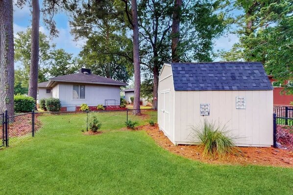 Ein Wohngebiet mit einer kleinen Gartenhütte, einem Haus und einem eingezäunten Hof.