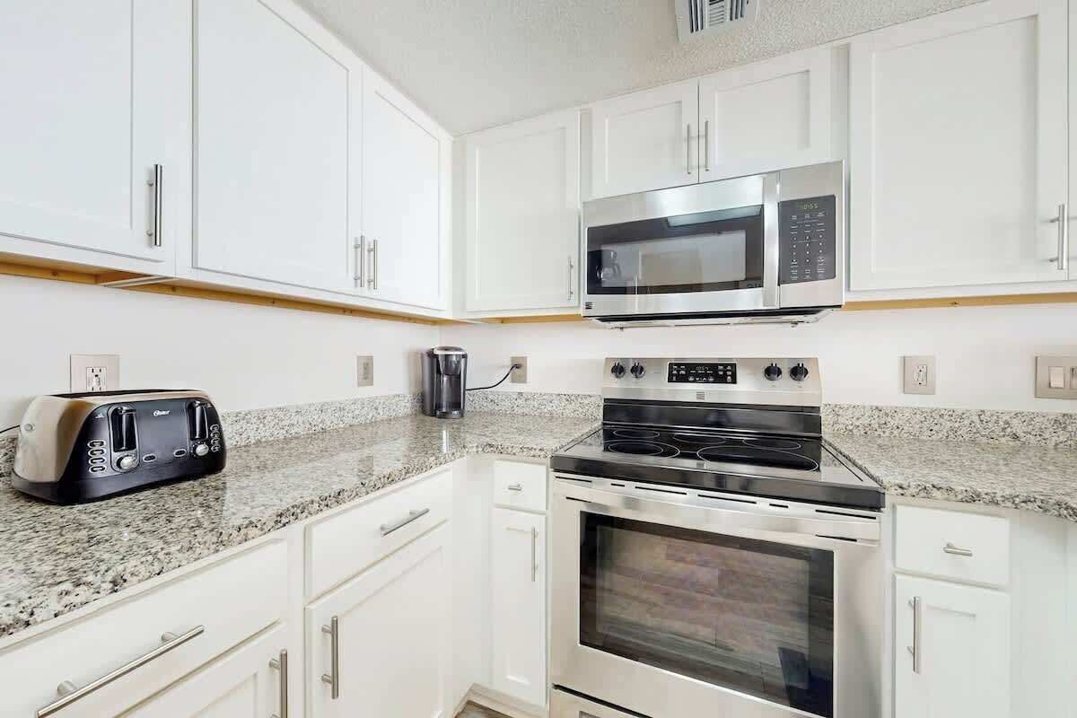 A kitchen with white cabinets, a microwave, a toaster, and a stove.