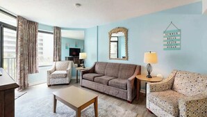 A living room with a sofa, armchairs, a coffee table, and a TV. - Golden Mile Condo Retreat (Myrtle Beach)