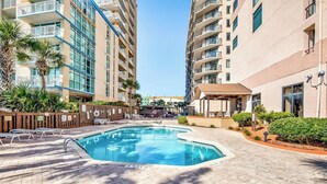 A swimming pool with lounge chairs, surrounded by high-rise buildings with balconies. - Golden Mile Condo Retreat (Myrtle Beach)