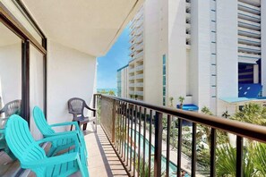 A balcony with turquoise chairs and a pool view. - Golden Mile Condo Retreat (Myrtle Beach)
