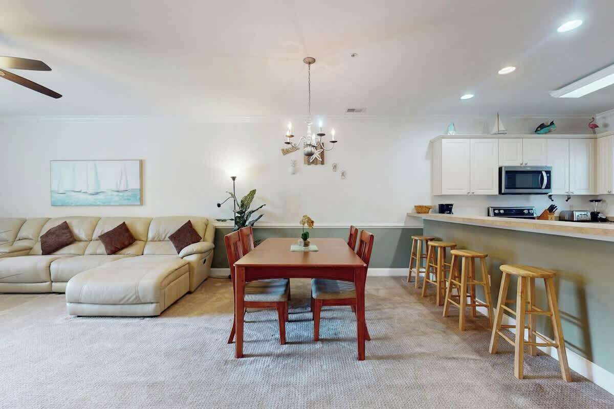 A modern living room with a sofa, dining table, and bar stools.