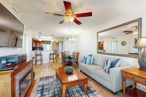 Ein Wohnzimmer mit Deckenventilator, einer Couch, einem Couchtisch und einem Essbereich mit Stühlen.