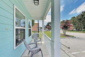 A porch with two chairs, a covered area, and a view of a street with trees and a parked car. - 324 Snorkel Way Condo (Myrtle Beach)