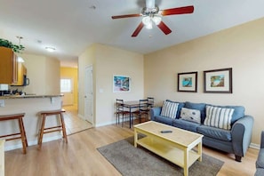 A living room with a sofa, a coffee table, and a dining area with chairs and a table. - 324 Snorkel Way Condo (Myrtle Beach)