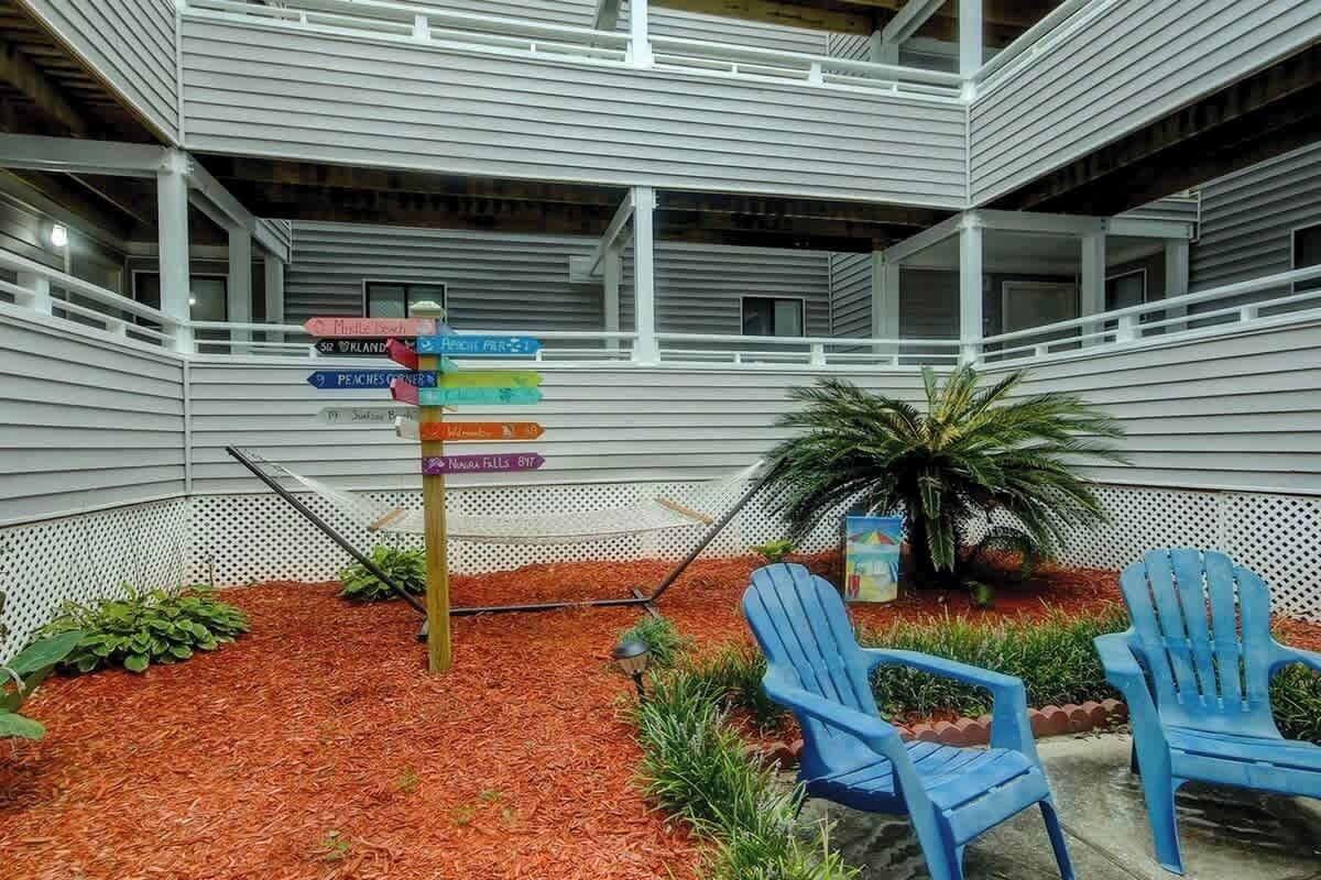 Een binnentuin met een bord met richtingaanwijzingen, twee blauwe stoelen en een kleine palmboom.