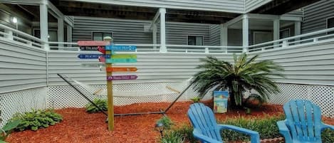An indoor courtyard with a directional signpost, two blue chairs, and a small palm tree.