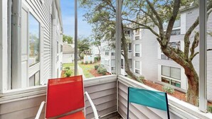 Ein Balkon mit Blick auf ein Wohngebiet, mit Baum und blauem Himmel.