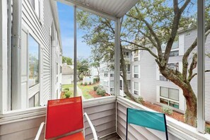 Ein Balkon mit Blick auf ein Wohngebiet, mit Baum und blauem Himmel.