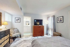 A bedroom with a bed, dresser, TV, chair, and a walk-in closet. - Arcadian Dunes 12-246 (Myrtle Beach)