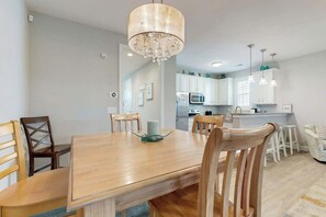A modern kitchen with white cabinets, a central island, and pendant lighting. - The Retreat Condo Home (North Myrtle Beach)