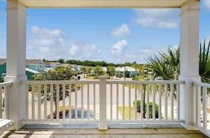 A covered porch with a view of a residential area, including houses and greenery. - The Retreat Condo Home (North Myrtle Beach)