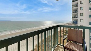 En balkon med udsigt over strand og hav.