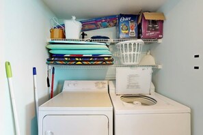 Un espace buanderie équipé d’un lave-linge, d’un sèche-linge et de paniers à linge empilés.