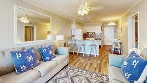 A modern living room with a sofa, chairs, and a dining area with a table and chairs. - A Place at the Beach VI - 305 (Myrtle Beach)