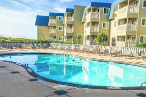 A swimming pool with lounge chairs and a building with balconies. - A Place at the Beach VI - 305 (Myrtle Beach)