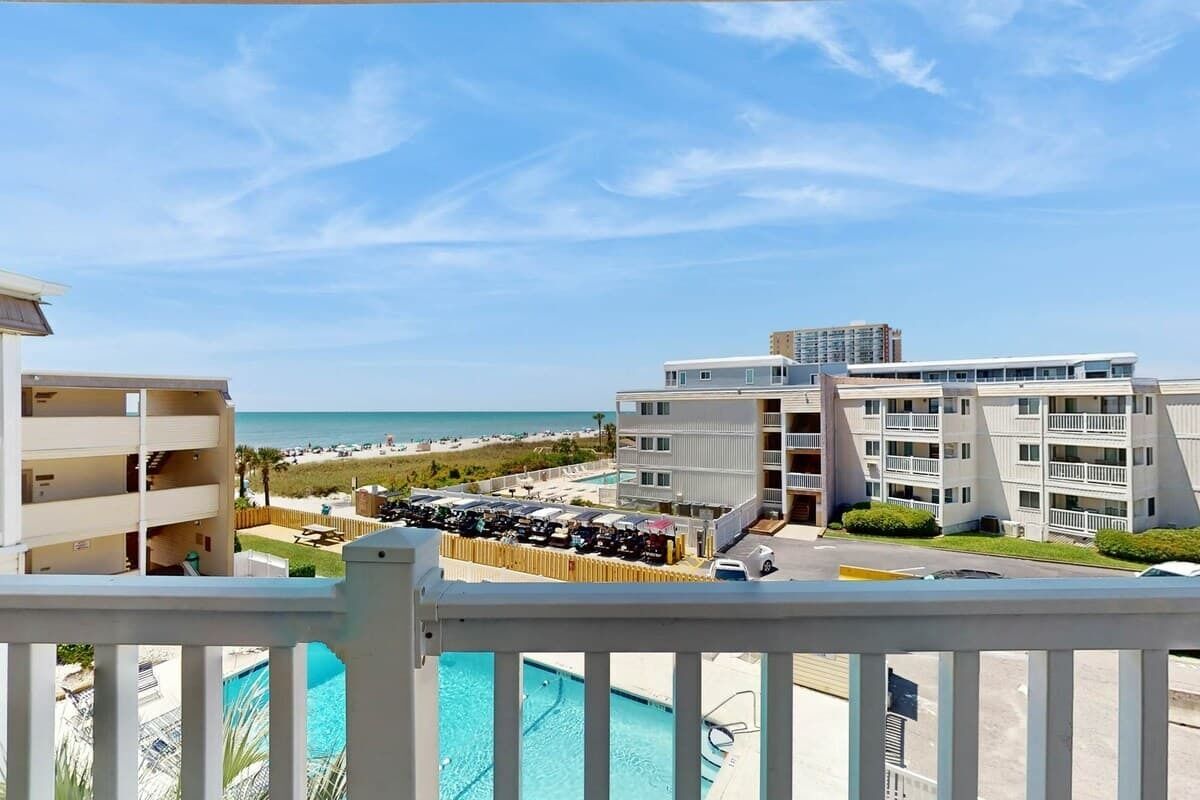 A hotel with a pool, beach view, and multiple balconies.