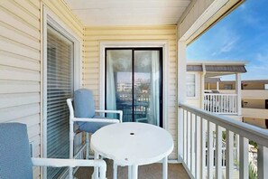 A balcony with a white table and two chairs, a sliding glass door, and a view of other buildings. - A Place at the Beach VI - 305 (Myrtle Beach)
