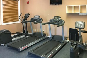 A gym with three treadmills, a wall-mounted TV, and a shelf with storage boxes. - Ocean Creek Plantation D-5 (Myrtle Beach)