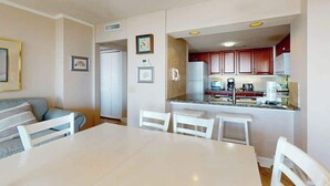 Una cuina moderna amb armaris vermells, un taulell blanc i una zona de menjador amb taula i cadires blanques.