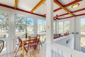 Ein Essbereich mit Holztisch und -stühlen, großen Fenstern und einem Deckenventilator.