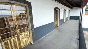 A corridor with a series of doors and windows, a tiled floor, and a ceiling with wooden beams. - Matlazinca Suite in downtown Toluca (Toluca de Lerdo)