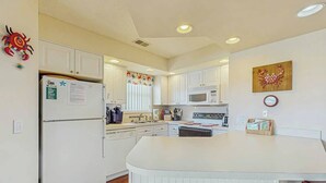 A kitchen with white cabinets, a microwave, and a refrigerator. - Shorehaven G-3 Unit Condo (North Myrtle Beach)
