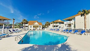 A swimming pool with lounge chairs and a building with balconies. - Shorehaven G-3 Unit Condo (North Myrtle Beach)