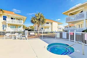 A pool area with a palm tree, white fences, and buildings with balconies. - Shorehaven G-3 Unit Condo (North Myrtle Beach)
