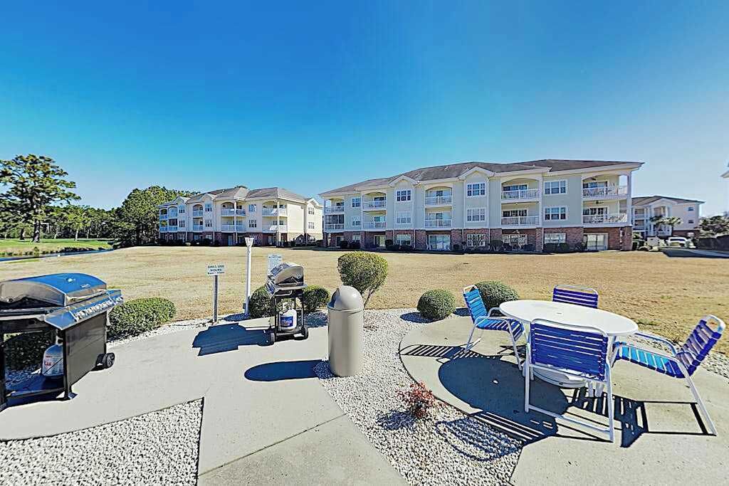 A hotel courtyard with outdoor seating, a barbecue grill, and a trash can.