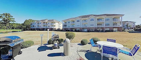 A hotel courtyard with outdoor seating, a barbecue grill, and a trash can.