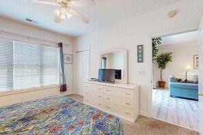 A bedroom with a bed, dresser, television, and a ceiling fan. - Oasis | Where Coastal Meets Calm (Myrtle Beach)