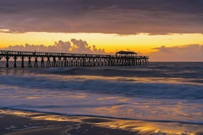 A pier extending into the sea with a sunset in the background. - Oasis | Where Coastal Meets Calm (Myrtle Beach)