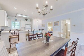A dining area with a wooden table, chairs, and a chandelier. - Oasis | Where Coastal Meets Calm (Myrtle Beach)