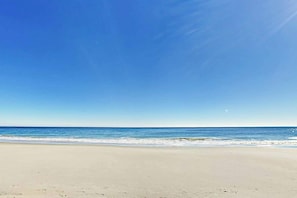 Ein Strand mit blauem Himmel und ruhiger See.