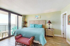 Ein Schlafzimmer mit Bett, Stuhl, Nachttisch, Lampe und Blick durch eine Schiebetür.