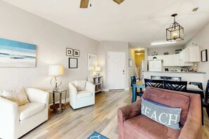 A living room with a sofa, armchairs, a coffee table, and a dining area with chairs and a table. - Seaside Unit C Condo (Surfside Beach)