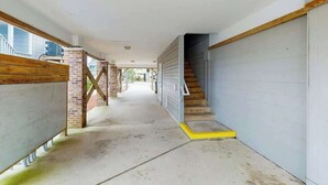 Un pasillo con una escalera que conduce a un garaje, un pilar de ladrillo y un suelo de hormigón.